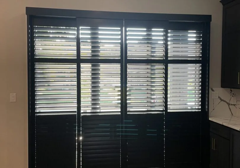 Black plantation shutters on a patio door installed by Shutter King USA in an Indianapolis home, a style available with Norman PerfectTilt motorization