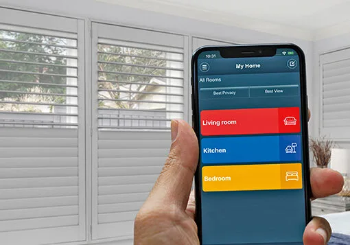 Homeowner controlling Norman motorized shutters from a smartphone app in an Indianapolis home