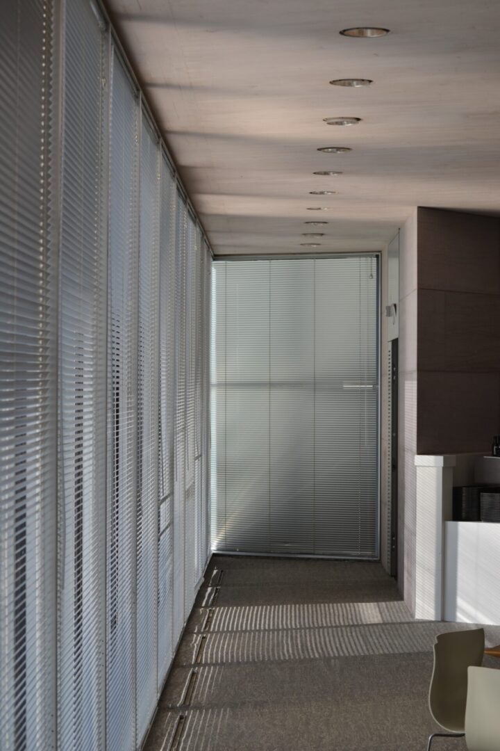 A hallway with a white wall and a glass door.