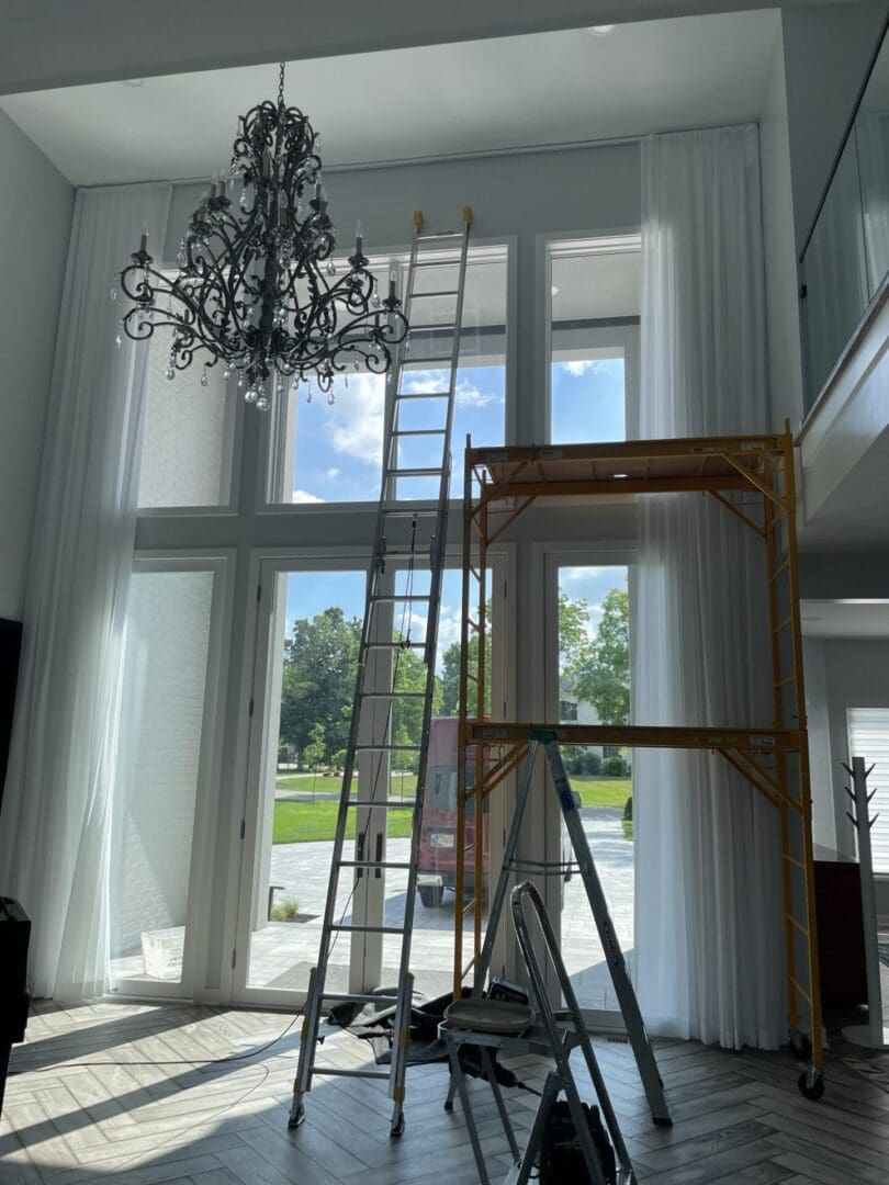 A ladder in the middle of a room with a chandelier.