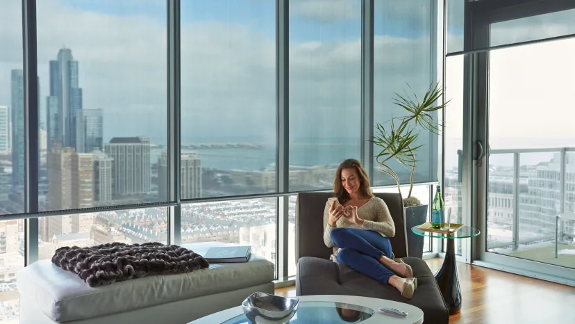 A woman sitting on top of a black couch in front of a window.