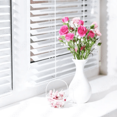 A white vase with pink flowers in it